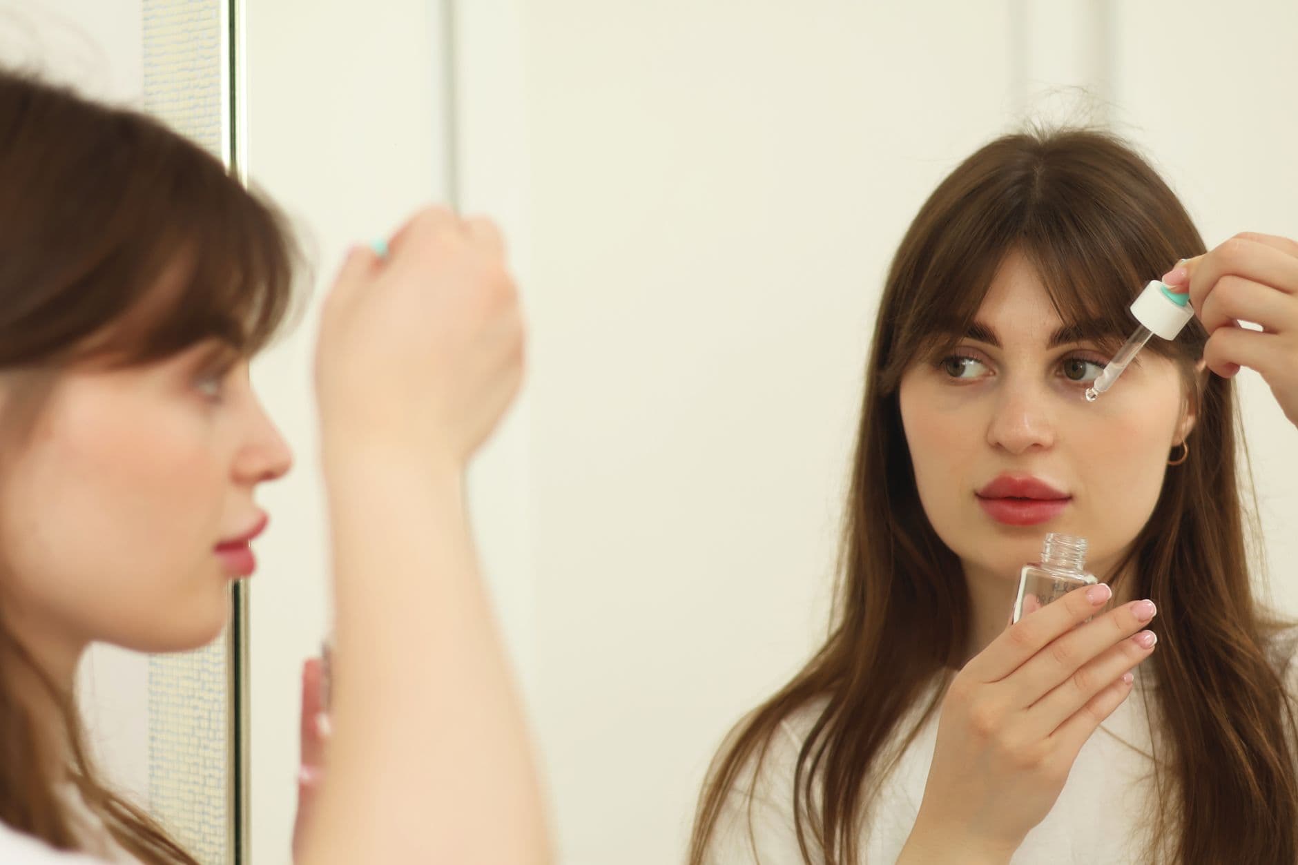 Bir kadın yüzüne serum uygulayarak cilt bakım rutinini sürdürüyor
